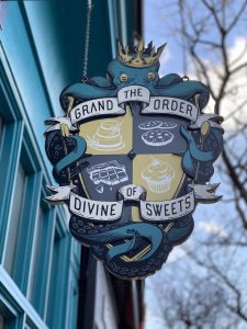 The Grand Order of Divine Sweets sign outside the cafe
